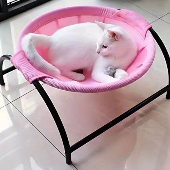 hamac pour chat de couleur rose sur un support noir en métal et de tissu maillé avec un chat blanc coucher dedans