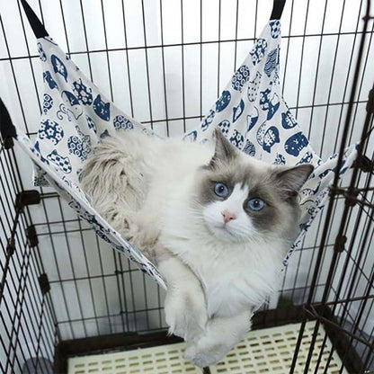 hamac pour chat installer dans une cage de couleur blanc avec des motifs bleu et un chat coucher dessus