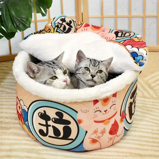 maison pour chat de style japonais avec un dessin de chat et il a deux petits chat dedans bien installer la forme est ronde et creuse