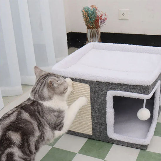 maison pour chat de couleur gris et blanc assez grand pour deux chat et on voit un chat faire ses griffe sur le petit griffoir qui est dessus sur le côté