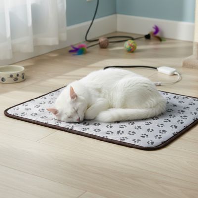 tapis pour chat de couleur gris avec motif de pattes avec un chat blanc qui dort dessus confortablement